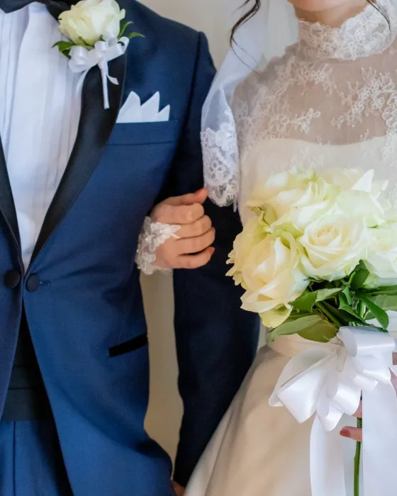 イメージ写真：白いブーケを持つ新婦と、腕を組む新郎
